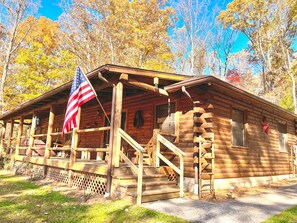 A wooden log cabin with a porch and a flag.