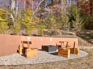 A wooden bench area with a gravel path, surrounded by a low wall and autumn foliage.