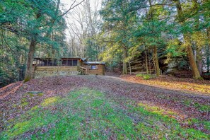 Une cabane rustique située dans une forêt, avec un chemin de gravier menant à celle-ci.