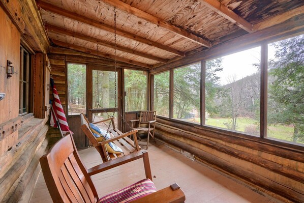 A wooden cabin with a porch, large windows, and a flag.