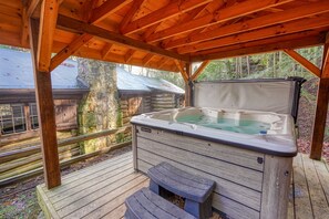 Un bain à remous sous une pergola en bois, avec vue sur un chalet rustique.