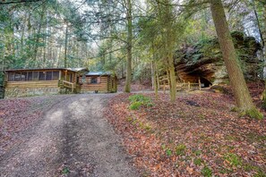 A rustic log cabin with a dirt path leading to it, surrounded by a forest. - Russell Cabin in Hocking Hills (South Bloomingville)