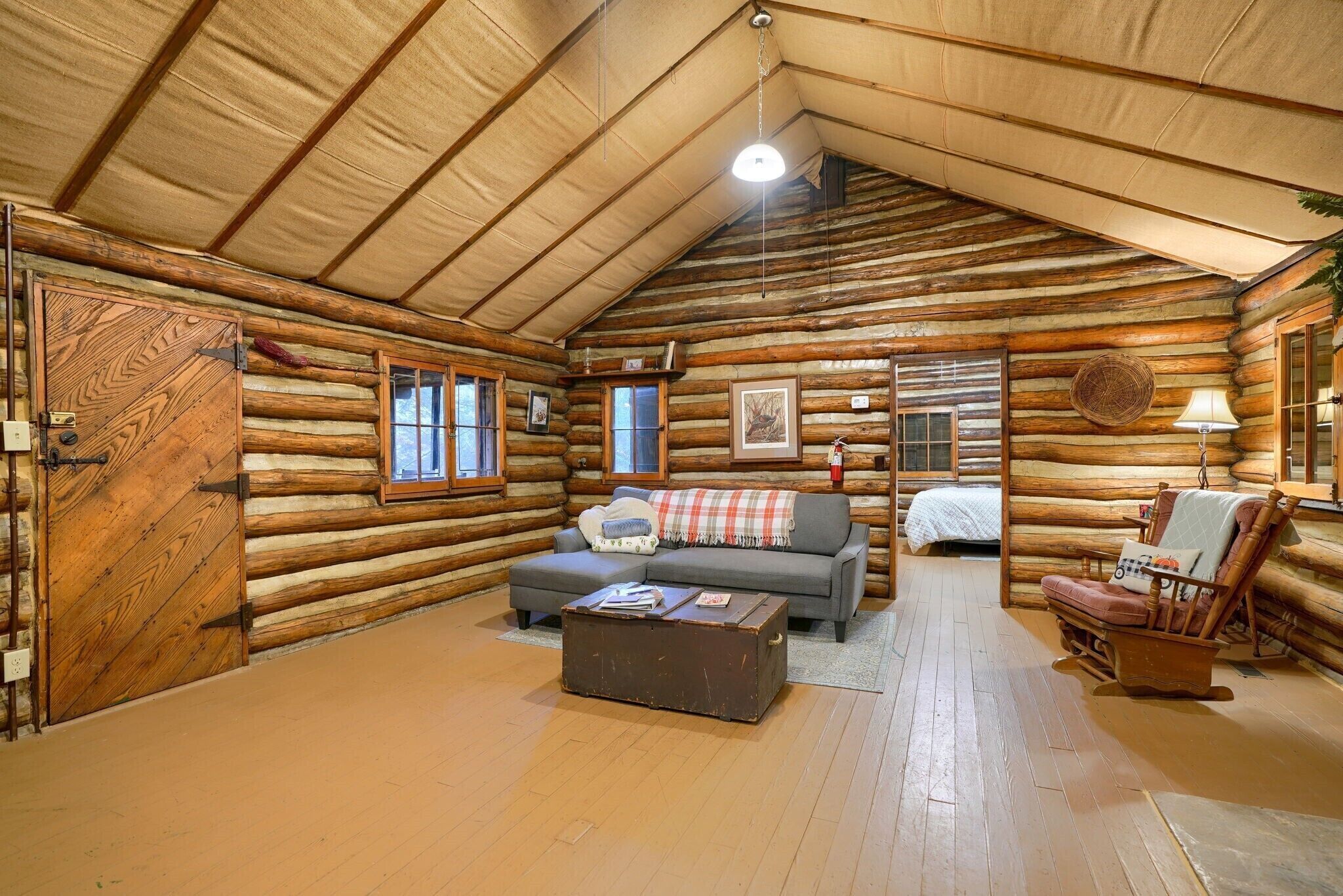 Interior de una cabaña de troncos con un sofá, un sillón y una mesita.