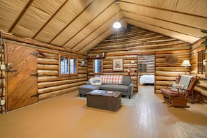 A log cabin interior with a sofa, armchair, and a small table.
