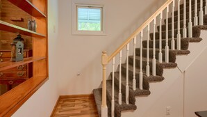 Eine Treppe mit hölzernen Geländern und Teppichstufen, die zu einer Zwischenebene mit einem kleinen Fenster führt.
