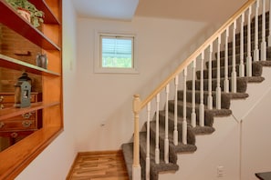 A staircase with wooden railings and carpeted steps, leading to a landing with a small window. - Hillside Hideaway in Hocking Hills (Logan)