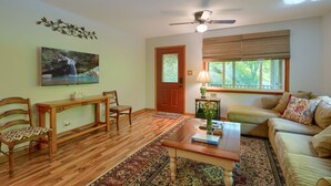 A living room with a wooden floor, a sofa, a coffee table, a fireplace, and a painting on the wall. - Hillside Hideaway in Hocking Hills (Logan)
