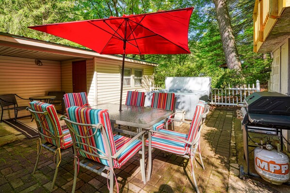 An outdoor patio with a table and chairs, a grill, and a propane tank.