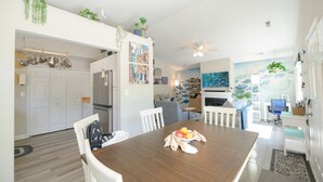 Een moderne keuken met witte kasten, een eettafel met een fruitschaal en een plafondventilator.