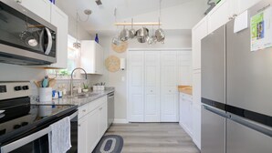 Een moderne keuken met witte kasten, roestvrijstalen apparatuur en een hangende keukengarderobe.