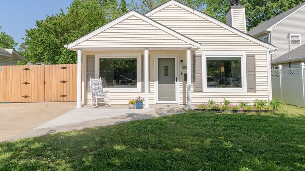 Een gelijkvloers huis met een veranda, een garage en een omheinde tuin.