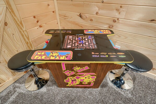 Pöydällä on labyrinttipeli ja Pac-Man-tarroja, ja taustalla näkyy puinen seinä.