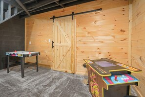 A room with a wooden door, a foosball table, and a table tennis table.