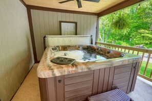 A hot tub with a wooden exterior and a view of greenery outside. - Hideaway Pines Cabin (Logan)