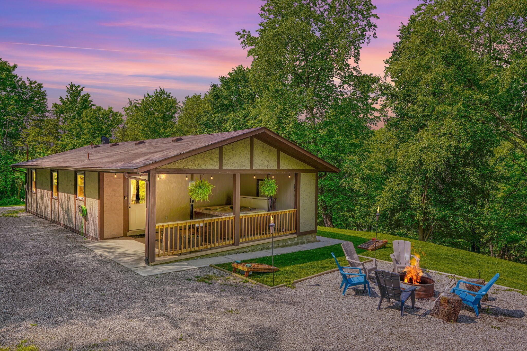 A cabin with a porch, outdoor seating, and a fire pit.