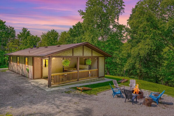 A cabin with a porch, outdoor seating, and a fire pit. - Hideaway Pines Cabin (Logan)