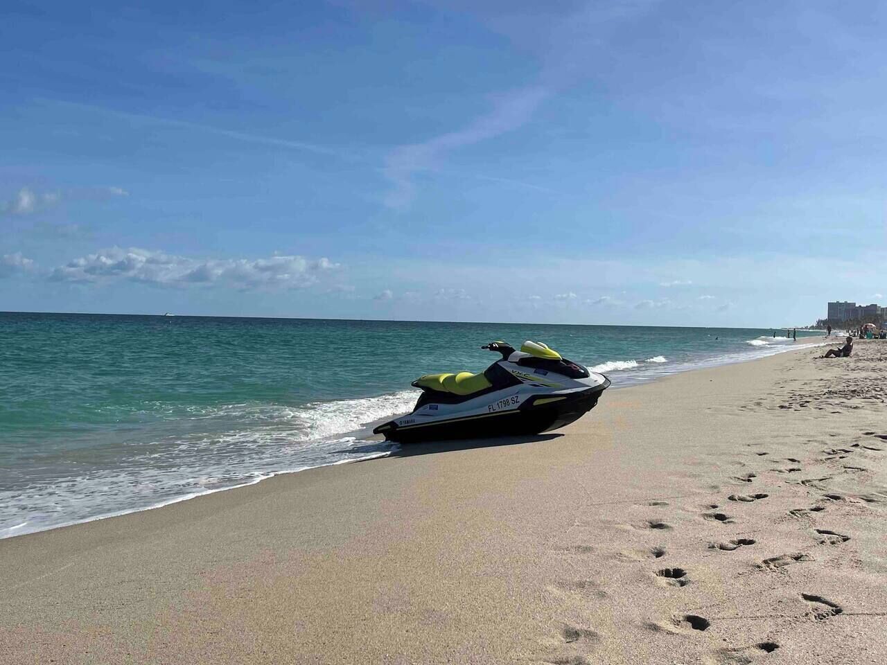 Un jet ski en una playa con el océano y una costa lejana.