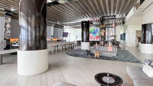 Een ruime lobby met een centraal ziteiland, grote pilaren en een modern plafondontwerp.