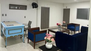 A modern hotel room with a desk, two blue armchairs, a coffee table, and a vase of flowers. - COOL HOUSE (Arauca)