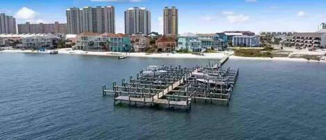 A marina with docks extending into the water, surrounded by high-rise buildings and a beach.