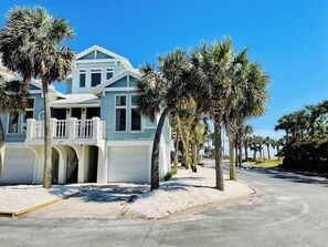 A two-story house with a balcony, surrounded by palm trees, and a clear sky. - Days Like This -spacious home steps from the beach (Navarre Beach)