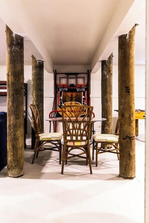 A narrow hallway with a table and chairs, wooden pillars, and a basketball hoop in the background. - Days Like This -spacious home steps from the beach (Navarre Beach)