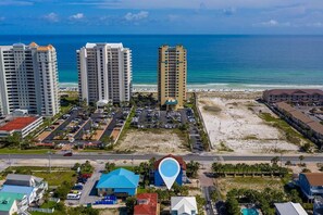 A coastal hotel area with multiple high-rise buildings, a parking lot, and a beach.