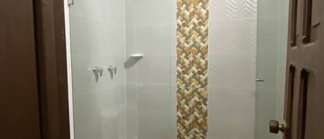 A bathroom with a shower, toilet, and a patterned wall.