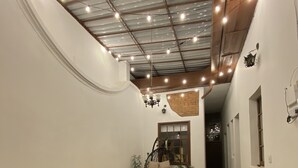 A spacious room with a high ceiling, exposed beams, and a patterned floor. There are several wooden tables and a hanging chair. - banana hostel (Bogotá)