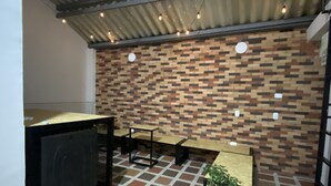 A covered outdoor seating area with a patterned floor, a brick wall, and string lights. - banana hostel (Bogotá)
