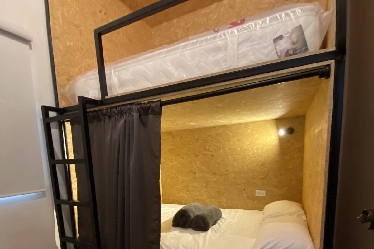 A bunk bed with a lower bunk and a mattress on the floor.
