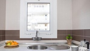 Eine Küche mit Fenster, Spüle, Obstschale und einer Pflanze.