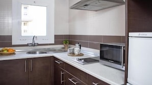 Eine moderne Küche mit dunklen Holzausbau, einer Edelstahl-Spüle, einer Mikrowelle und einem Kühlschrank.
