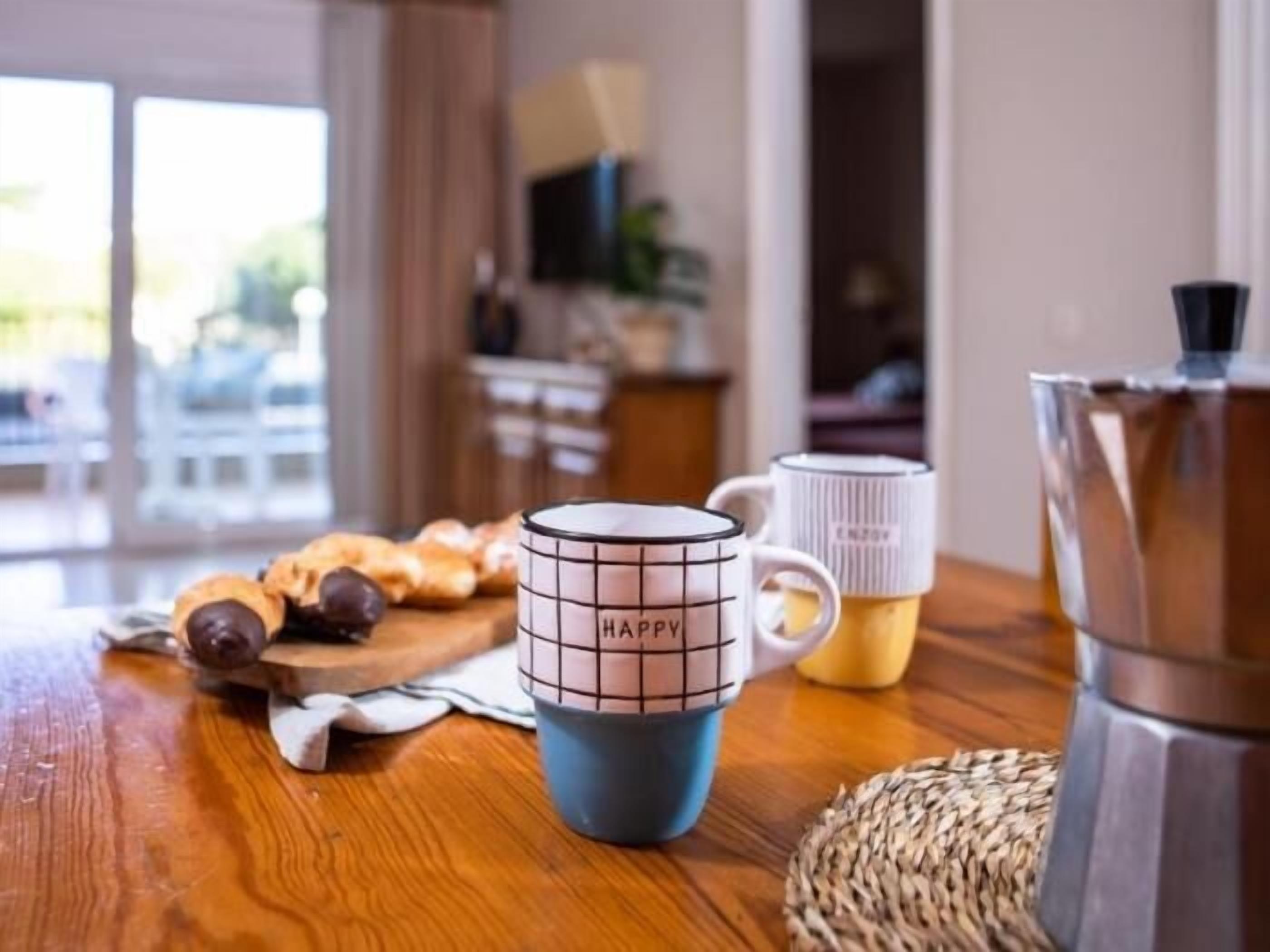 Eine Küche mit Kaffeemaschine, zwei Tassen und einem Holztisch.