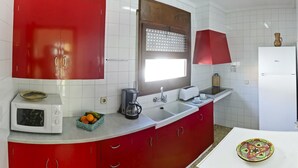 Eine Küche mit roten Schränken, einer weißen Mikrowelle, einer Kaffeemaschine und einem Toaster.
