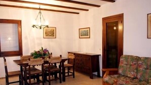 Un comedor con muebles de madera, una araña y dos cuadros en la pared.