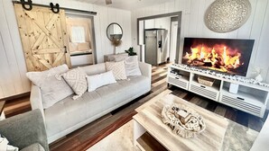 A living room with a sofa, coffee table, TV, and a fireplace. - Pet Friendly • Sleeps 8 • West PCB (Panama City Beach)