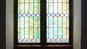 A stained glass window with a geometric pattern, a wooden frame, and a carpeted floor. - The Loft on Lundy | Short North Arts District (Columbus)