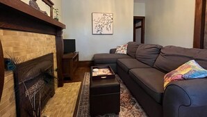 A living room with a fireplace, a sofa, a coffee table, and a rug.