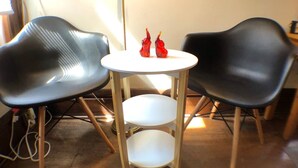 Une petite pièce avec deux chaises noires et une table blanche à trois étagères.