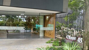 Entrada de un edificio moderno con puerta de vidrio, un camino pavimentado y un letrero que dice 