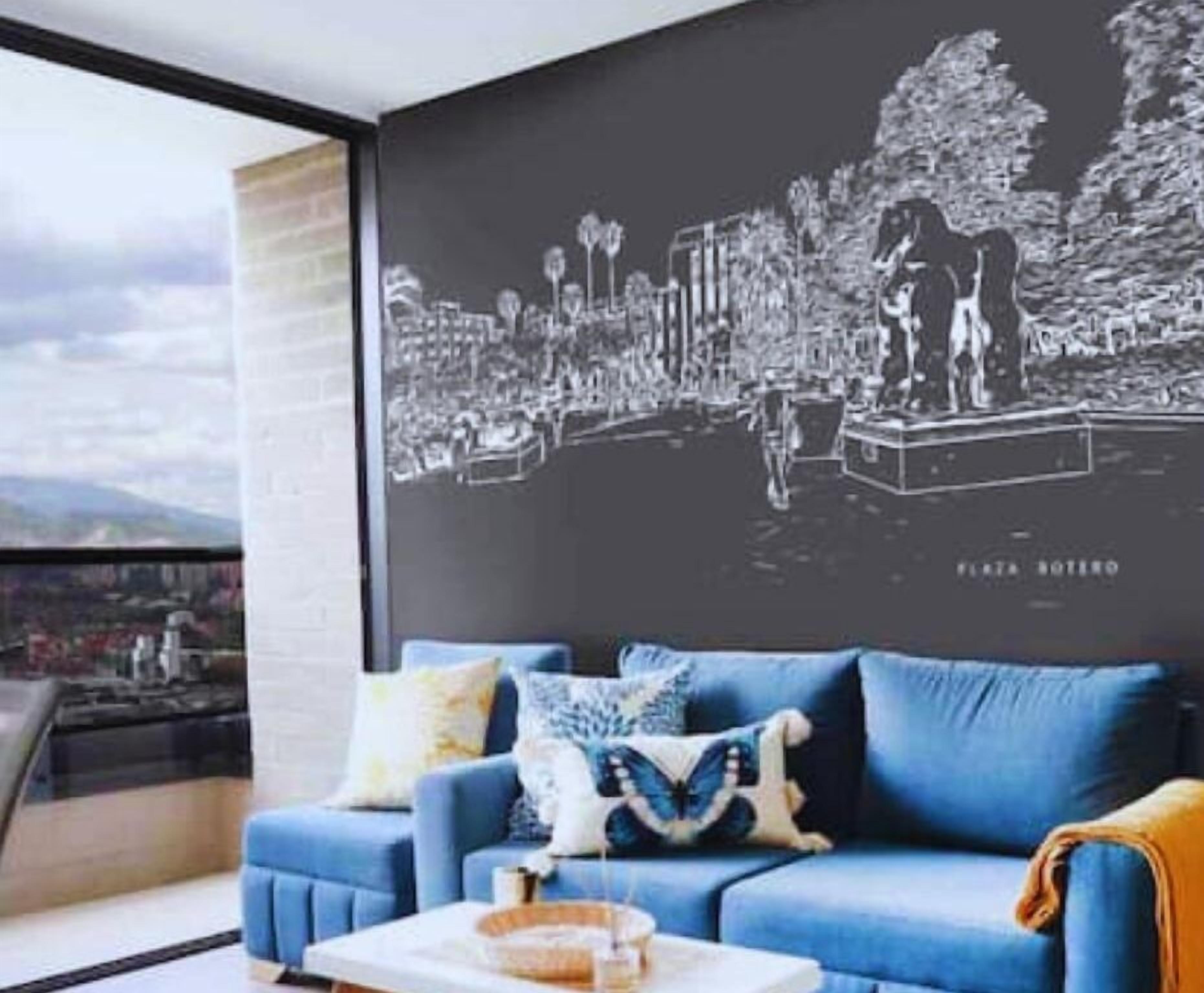 A modern living room with a blue sofa, a coffee table, and a black and white cityscape mural on the wall.