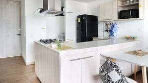 Una cocina moderna con una isla central, un refrigerador negro y armarios de madera.