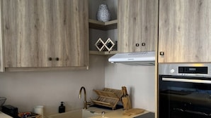 Une cuisine moderne avec des meubles de rangement en bois, un four encastré et un luminaire suspendu.