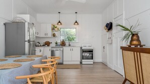 Una cucina moderna con mobili bianchi, un frigorifero grigio, un fornello e un'area pranzo con tavolo e sedie.