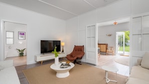 Un salon moderne avec un téléviseur à écran plat, un fauteuil en cuir et une table basse.