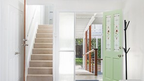 A staircase leading to a covered outdoor area with a green door and a coat rack. - Whalesong - by Lifestyle. Brunswick Heads (NEW BRIGHTON)