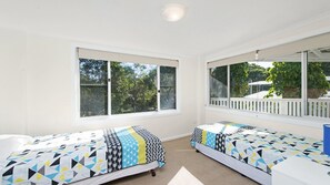 A room with two beds, large windows, and a view of the outdoors. - Whalesong - by Lifestyle. Brunswick Heads (NEW BRIGHTON)