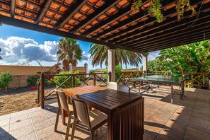 Una terrazza esterna con tavolo da ping pong, sedie e un pergolato.