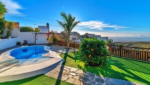 A swimming pool, green lawn, and a view of a coastal town. - Holiday Home "Bernarda" with Heated Pool, Sea Views, Private Pool and Wi-Fi (Villa de Arico)
